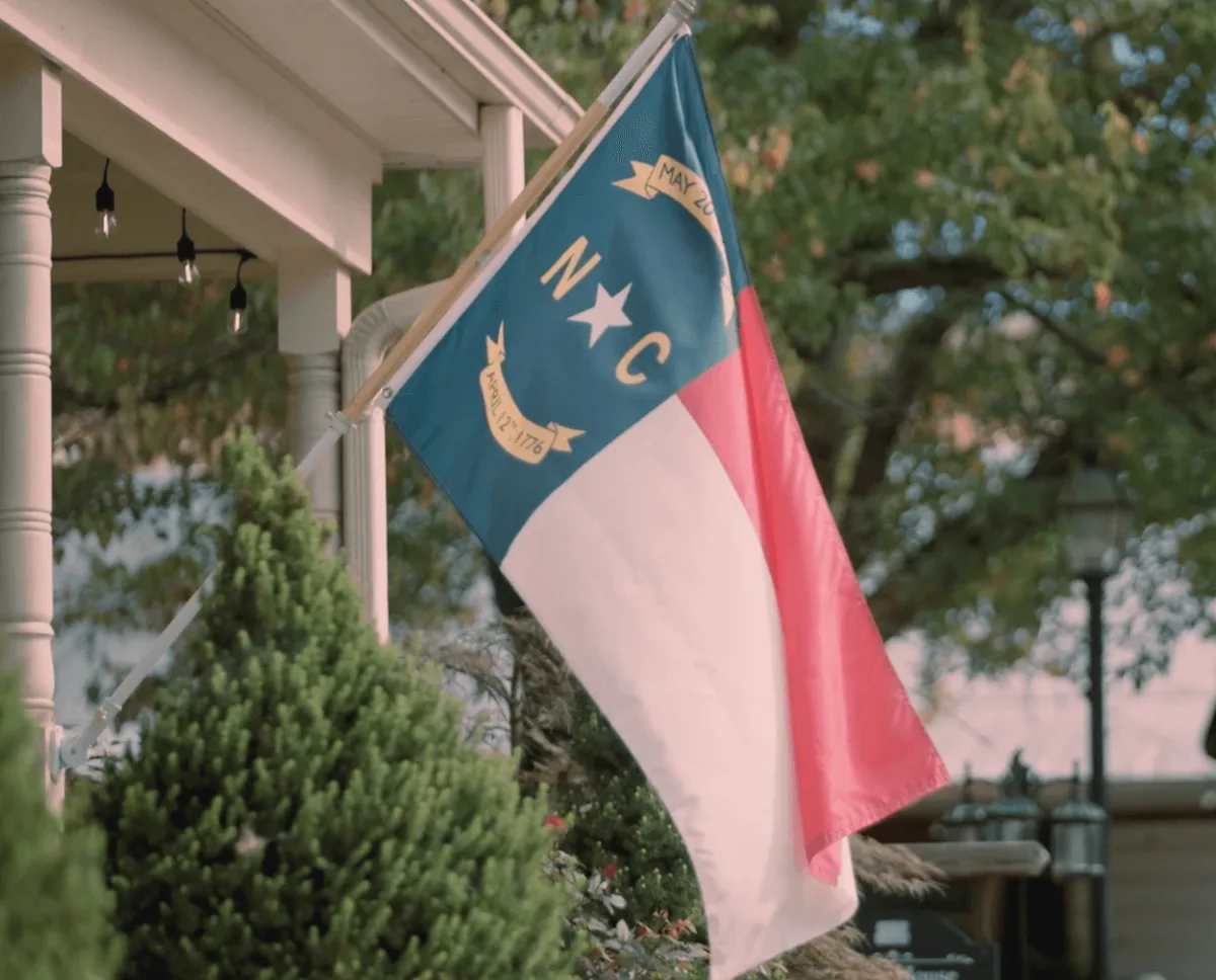 A North Carolina state flag hanging from a porch.
